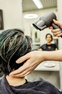 Hairdresser in a hairdressing salon blow-drying the dyed hair of a customer