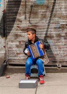 A boy playing the accordion on the road