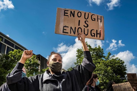 Dark-skinned demonstrator with poster with the inscription Enough is Enough
