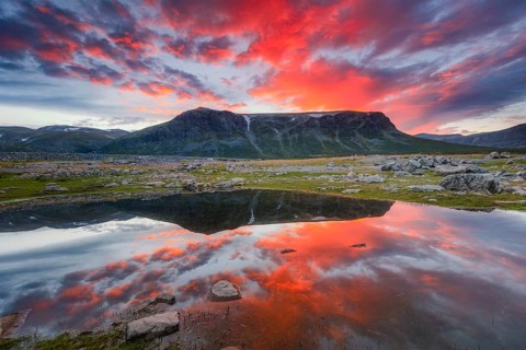 Mountain range reflected in the lake in evening mood with red clouds