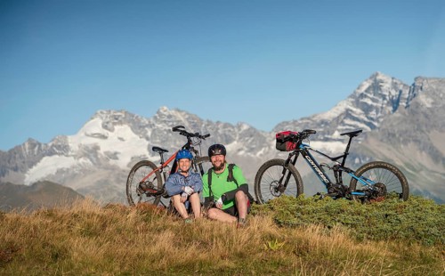 Mountain biker couple sitting next to eBikes in the autumnal mountain scenery of the Stubaier Alps