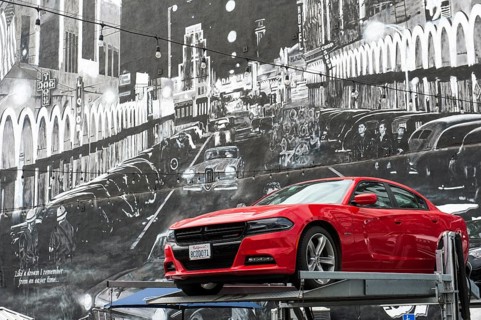 Red Dodge sports car in front of mural