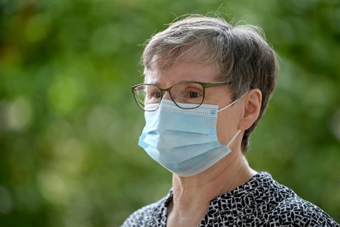 Elderly woman wears mouth mask correctly over nose and mouth