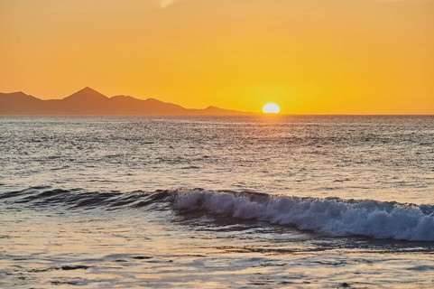 Beach Playa de la Pared with rocky coast at sunset