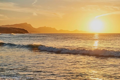 Beach Playa de la Pared with rocky coast at sunset