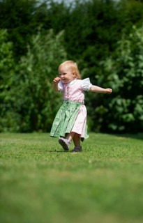 Girl in Dirndl runs across a meadow