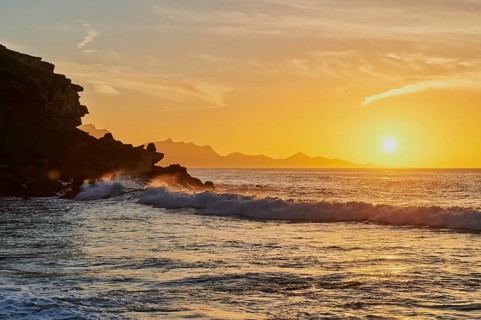 Beach Playa de la Pared with rocky coast at sunset