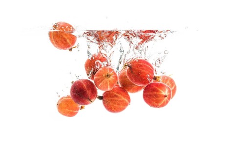 Red gooseberries fall into the water