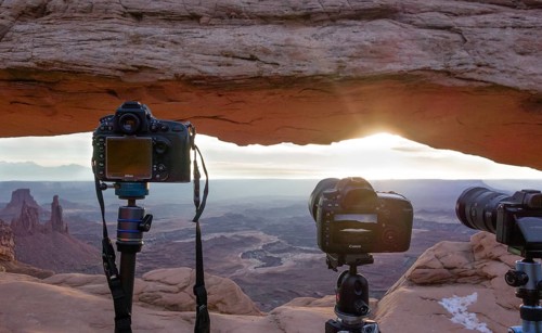 Cameras with view through Mesa Arch at sunrise