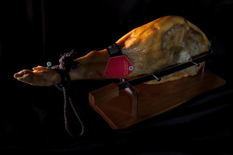 A piece of Jamon Serrano in a wooden board for cutting