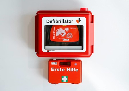 Defibrillator and first aid kit hanging on a wall in public space at Duesseldorf Airport