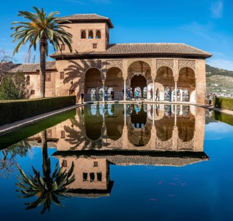 Historic building El Partal with pool and palm trees