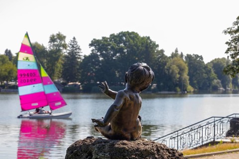 Statue on the beach promenade at Waginger See with sailing boat