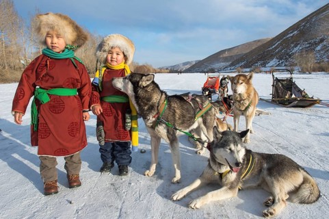 Children with huskies in front of dog sled