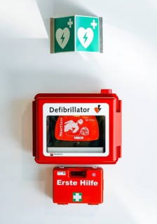 Defibrillator and first aid kit hanging on a wall in public space at Duesseldorf Airport