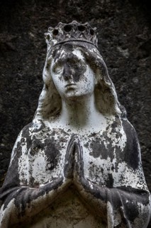 Weathered figure of the Virgin Mary on a grave