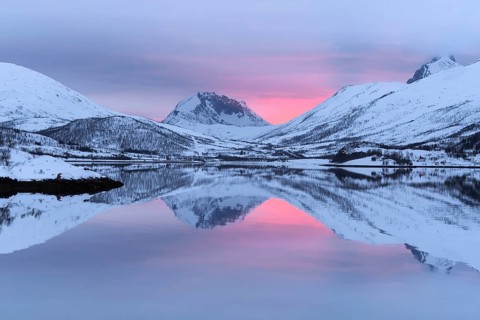 Snow-covered peaks in the evening light reflected in the lake