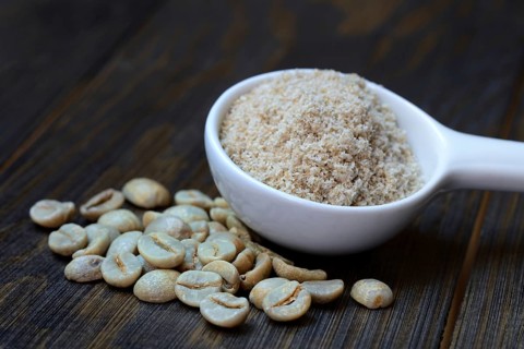 Green coffee beans and unroasted coffee powder in spoon