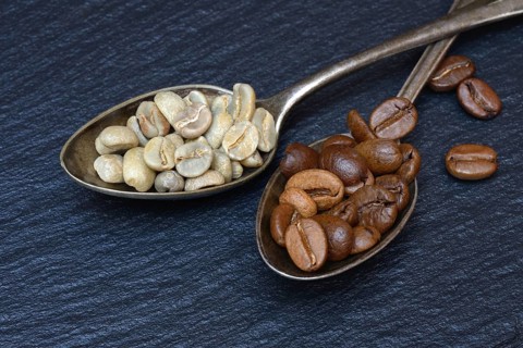 Green coffee and roasted coffee beans in spoon