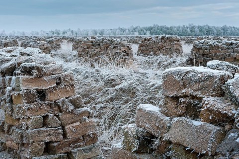 Piled up peat sods in the bog in winter at hoarfrost