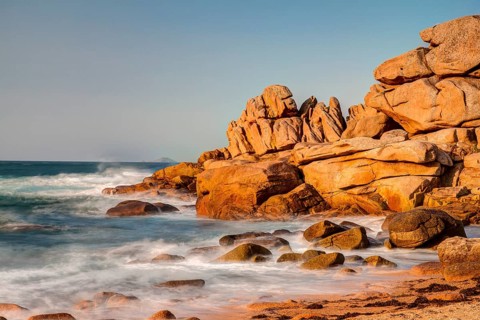 Red granite rocks and rough sea