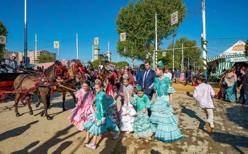 Spanish family with colourful flamenco dresses in front of marquees