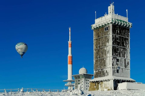 Hot-air balloon with transmitter mast and Brocken hostel on the winter snow-covered Brocken
