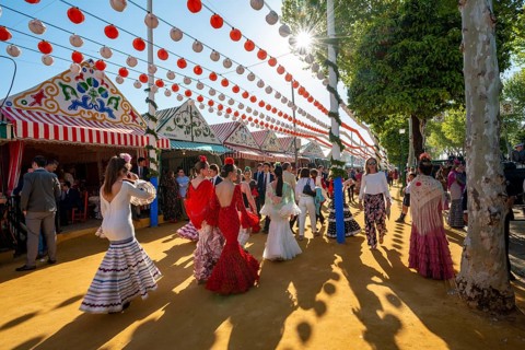 Spanish women with colorful flamenco dresses in front of marquees