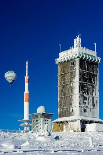 Hot-air balloon with transmitter mast and Brocken hostel on the winter snow-covered Brocken
