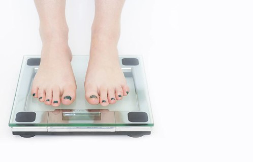 Woman in a weighing machine with white background