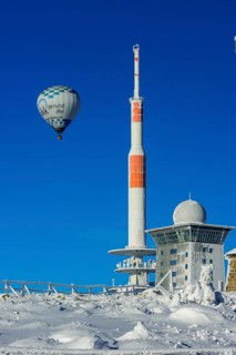Hot-air balloon with transmitter mast and Brocken hostel on the winter snow-covered Brocken