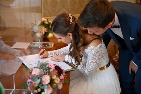 Bridal couple signs marriage certificate at the registry office