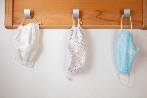 Various corona protection masks hang on coat hooks
