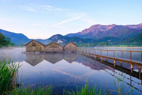 Boathouses and jetty in Lake Kochel near Schlehdorf in the morning light