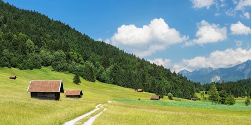 Path through a meadow with hay barns at the Geroldsee