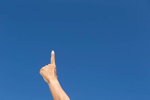 Finger raised against blue sky