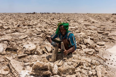 Afar nomad with knife cutting out salt plates