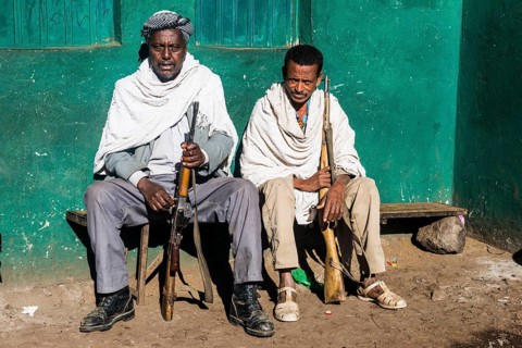 Two sentries with rifles sitting on a bench