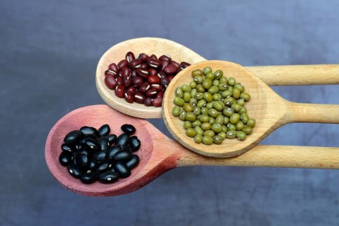 Black and red beans and green mung beans on wooden spoon