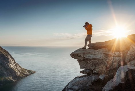 Photographer in front of sun on rocky outcrop