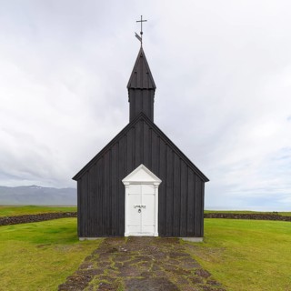 Traditional black church with white wooden door and stone wall