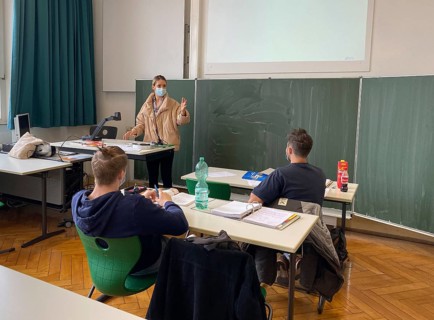Teacher with thick winter jacket and face mask in classroom teaching