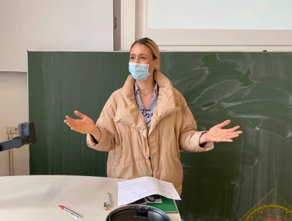 Teacher with thick winter jacket and face mask in classroom teaching
