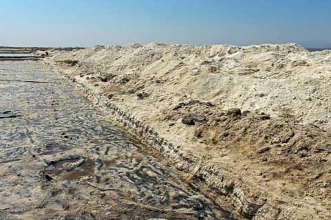 Harvested rock salt at the edge of an evaporation basin of a salt works