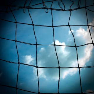 Football goal net against cloudy sky