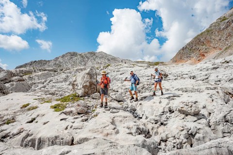 Three hikers in a landscape of washed-out karst rocks