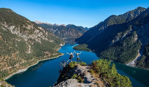 Two hikers stretch arms in the air