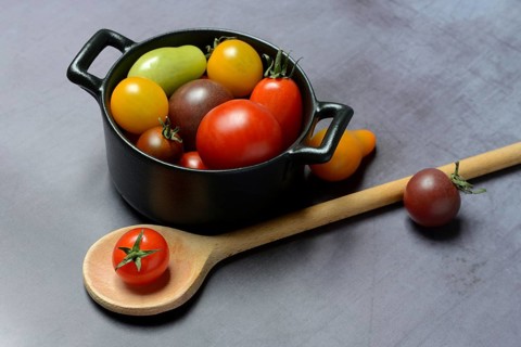 Different cherry tomatoes in pot with cooking spoon