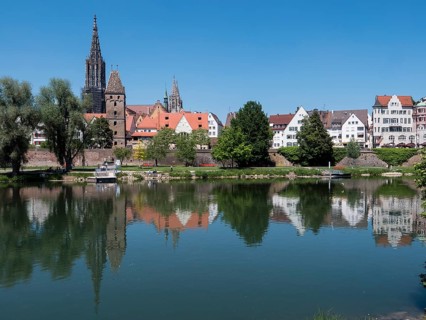 Ulm Cathedral and buildings on the banks of the Danube with water reflection