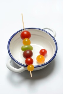 Various cherry tomatoes on wooden skewers on a bowl